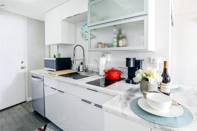 kitchen featuring black electric stovetop, dishwasher, light countertops, white cabinetry, and a sink