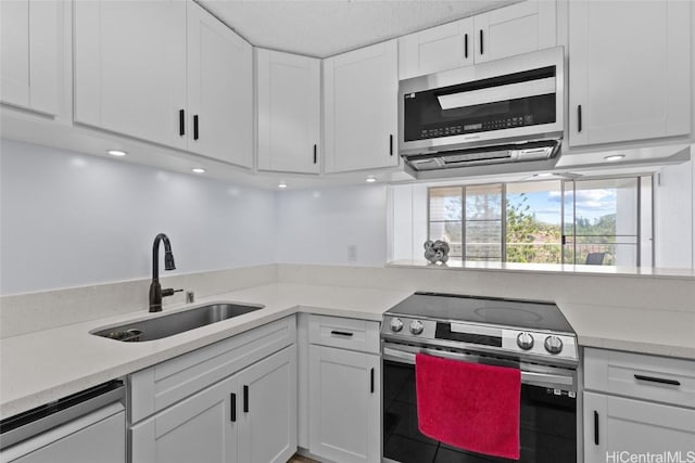 kitchen with white cabinets, stainless steel appliances, light countertops, and a sink