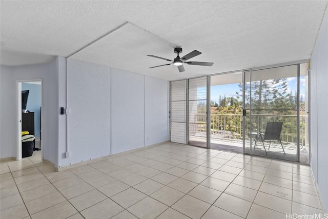 spare room featuring light tile patterned floors, a textured ceiling, ceiling fan, and expansive windows