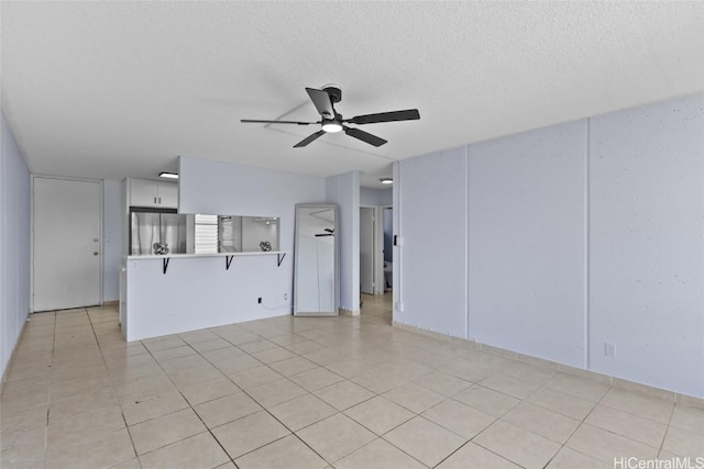 unfurnished living room with a textured ceiling, light tile patterned floors, and ceiling fan