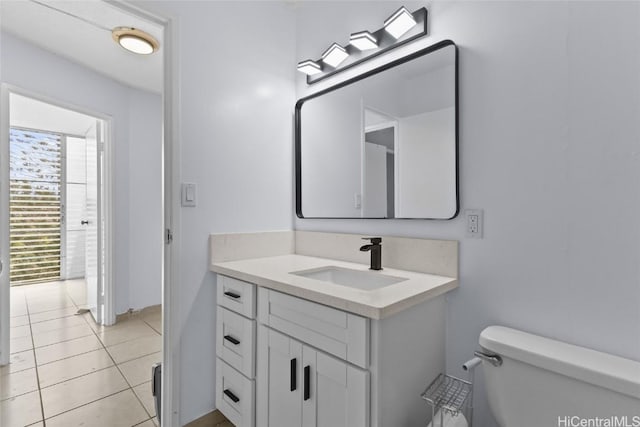 half bathroom with tile patterned flooring, toilet, and vanity