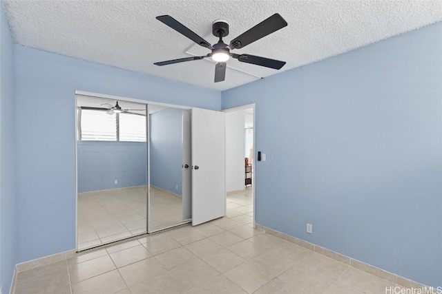 unfurnished bedroom with ceiling fan, a closet, a textured ceiling, and light tile patterned flooring