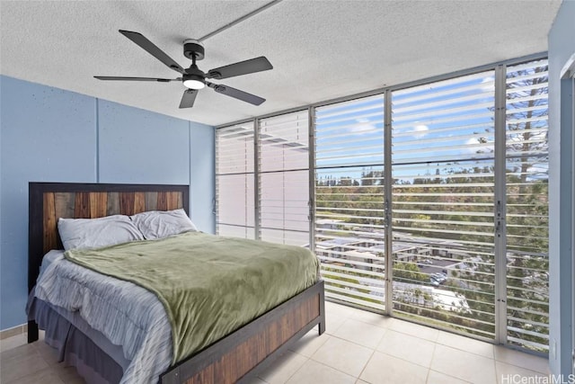 bedroom featuring light tile patterned floors, a textured ceiling, a ceiling fan, and expansive windows