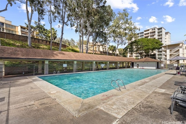 community pool with a patio area and fence