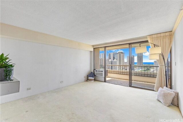 carpeted empty room with cooling unit, a textured ceiling, a view of city, and expansive windows