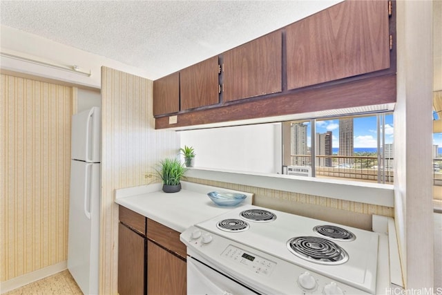 kitchen featuring white appliances, baseboards, wallpapered walls, light countertops, and a textured ceiling