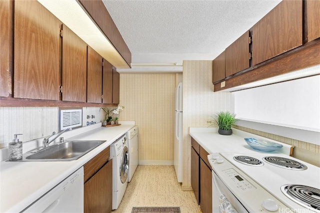 kitchen featuring white appliances, washer / dryer, a sink, light countertops, and a textured ceiling