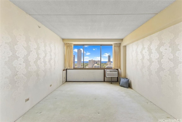 carpeted empty room featuring a city view, an AC wall unit, and a textured ceiling