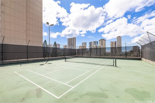 view of sport court featuring a city view and fence