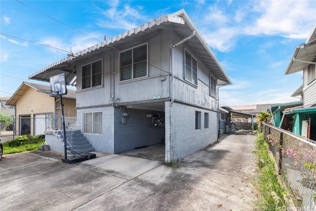 view of side of home with concrete block siding and fence