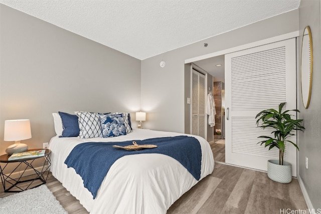 bedroom featuring a closet, a textured ceiling, baseboards, and wood finished floors