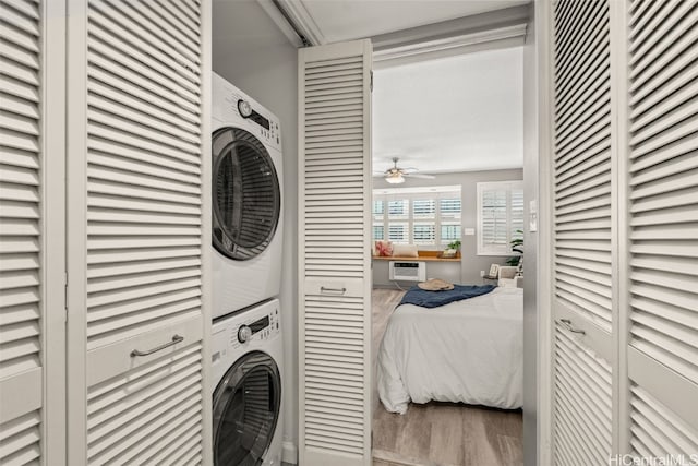 laundry area with ceiling fan, wood finished floors, laundry area, and stacked washer / dryer