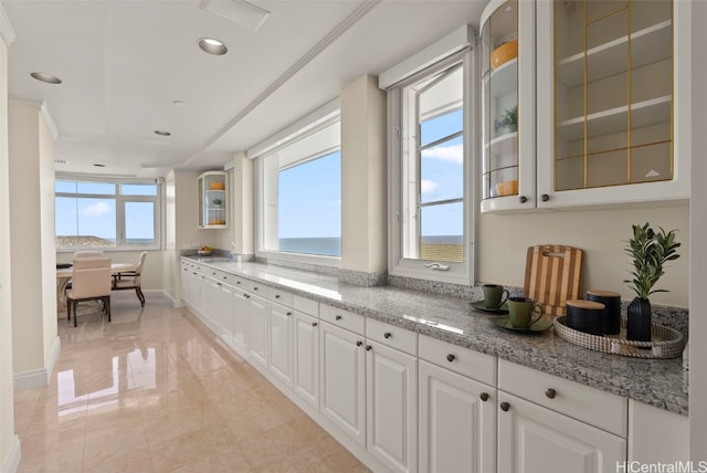 kitchen featuring light stone counters, baseboards, recessed lighting, white cabinets, and glass insert cabinets