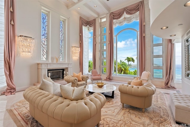 living area featuring baseboards, ornamental molding, beam ceiling, a fireplace, and a high ceiling