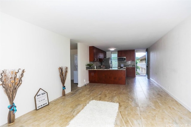 kitchen featuring stainless steel microwave, tasteful backsplash, open floor plan, fridge, and a peninsula