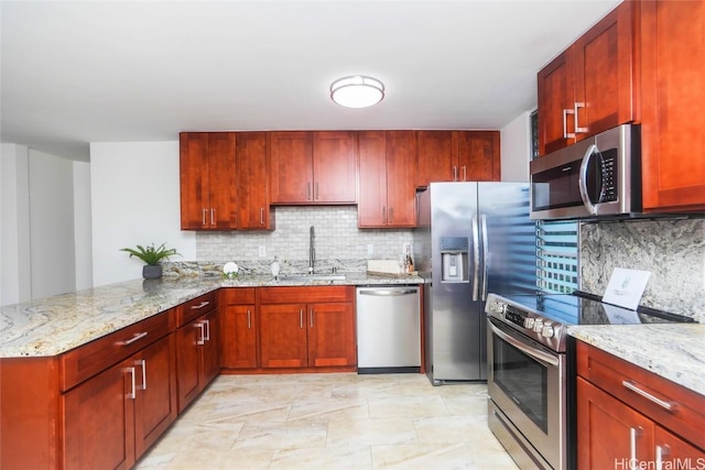 kitchen with light stone counters, a peninsula, a sink, stainless steel appliances, and tasteful backsplash