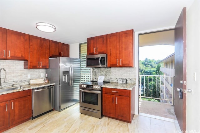 kitchen featuring a sink, stainless steel appliances, light stone counters, and tasteful backsplash