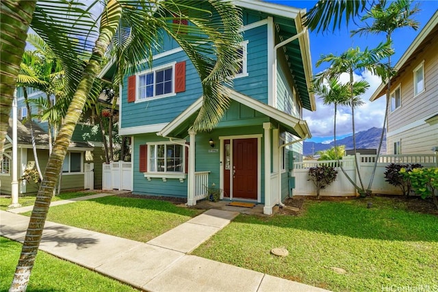 view of front of house featuring a mountain view, a front lawn, and fence