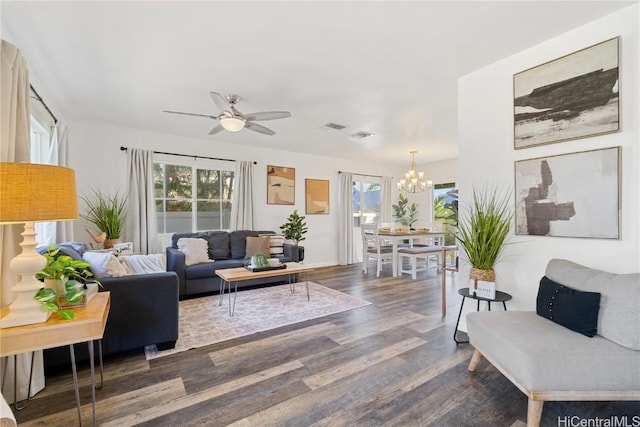 living area with plenty of natural light, ceiling fan with notable chandelier, visible vents, and dark wood-style flooring