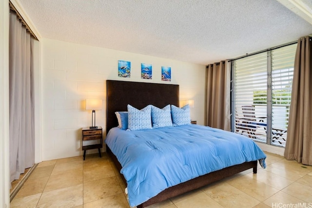 bedroom featuring tile patterned flooring, a textured ceiling, and concrete block wall