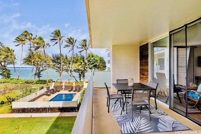 balcony with outdoor dining area, a water view, and a patio