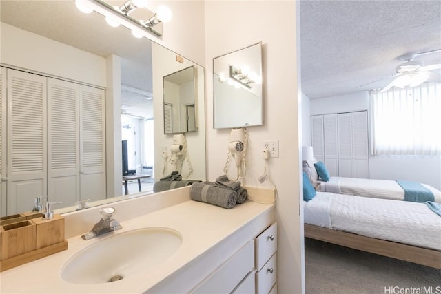 bathroom with vanity, a ceiling fan, a closet, a textured ceiling, and connected bathroom