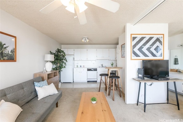 living area featuring a ceiling fan, light colored carpet, and a textured ceiling