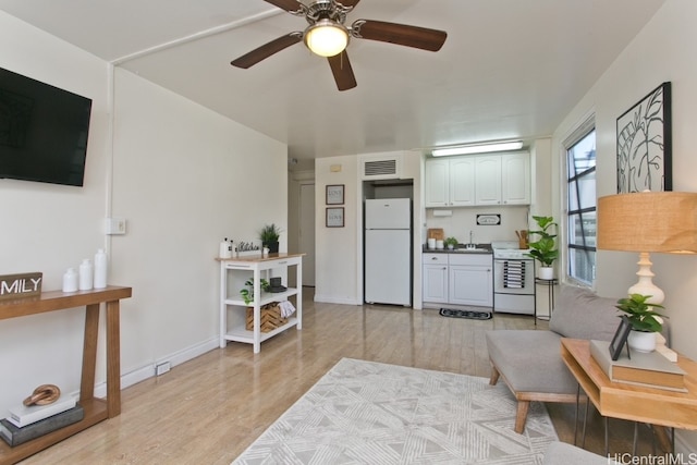 living area featuring a ceiling fan, baseboards, visible vents, and light wood finished floors