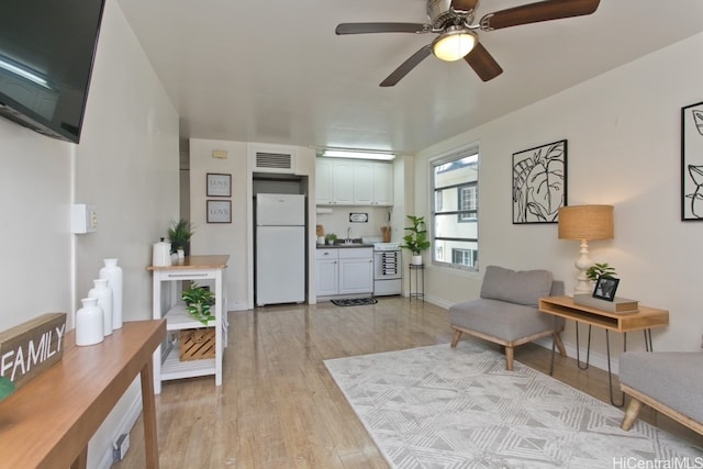 sitting room featuring a ceiling fan, baseboards, visible vents, and light wood finished floors