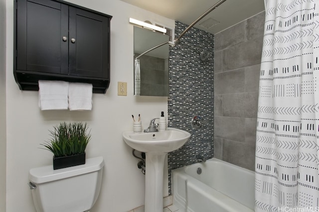 bathroom featuring a sink, shower / tub combo with curtain, and toilet