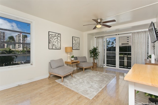 sitting room with baseboards, a ceiling fan, and wood finished floors