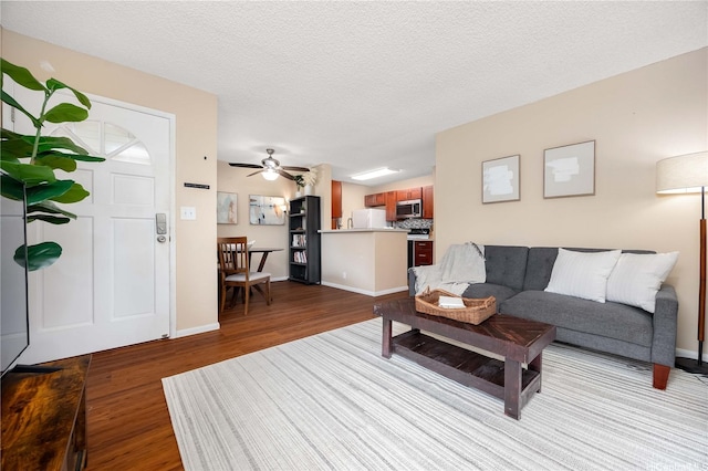 living room featuring a ceiling fan, baseboards, wood finished floors, and a textured ceiling