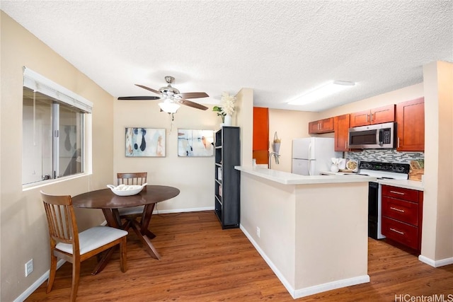 kitchen with stainless steel microwave, range with electric stovetop, wood finished floors, and freestanding refrigerator