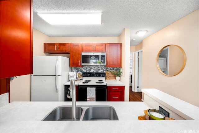 kitchen with stainless steel microwave, light countertops, range with electric stovetop, freestanding refrigerator, and a sink