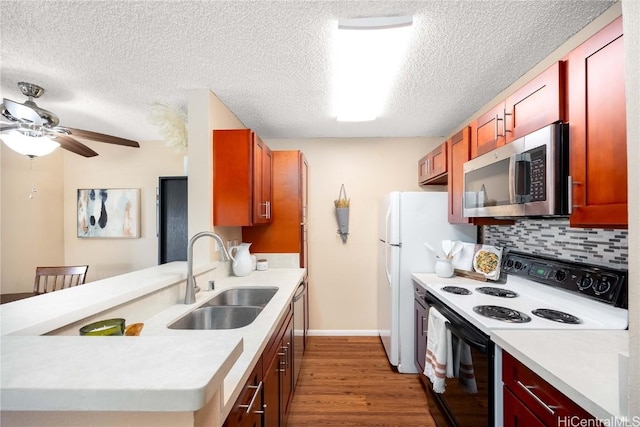 kitchen featuring stainless steel microwave, light wood-type flooring, electric range oven, decorative backsplash, and a sink