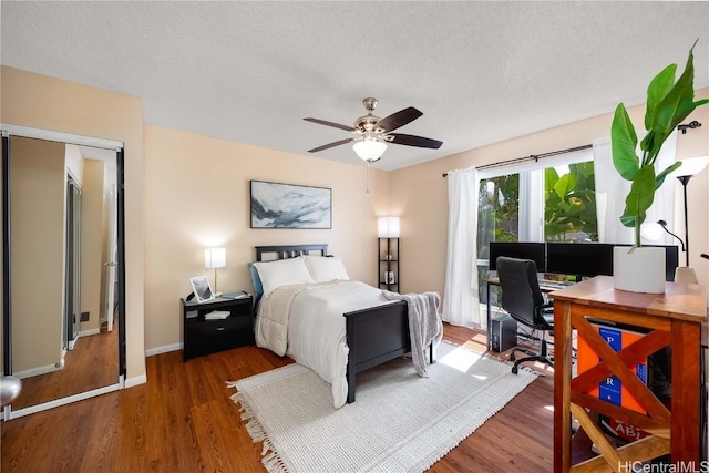 bedroom with access to outside, a textured ceiling, wood finished floors, baseboards, and ceiling fan