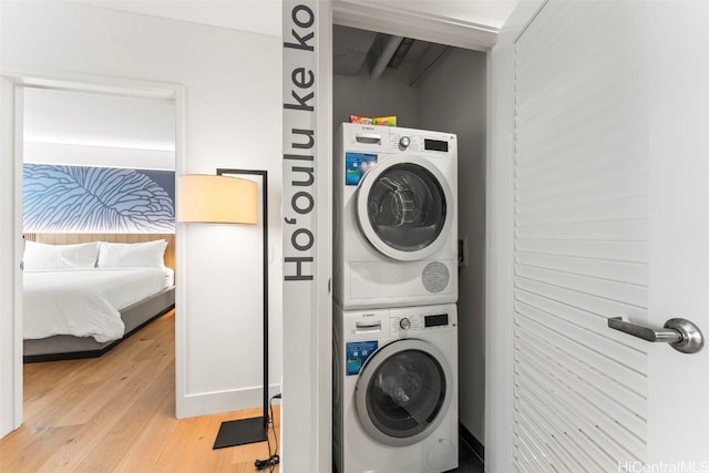 washroom featuring laundry area, light wood-style flooring, and stacked washer and clothes dryer