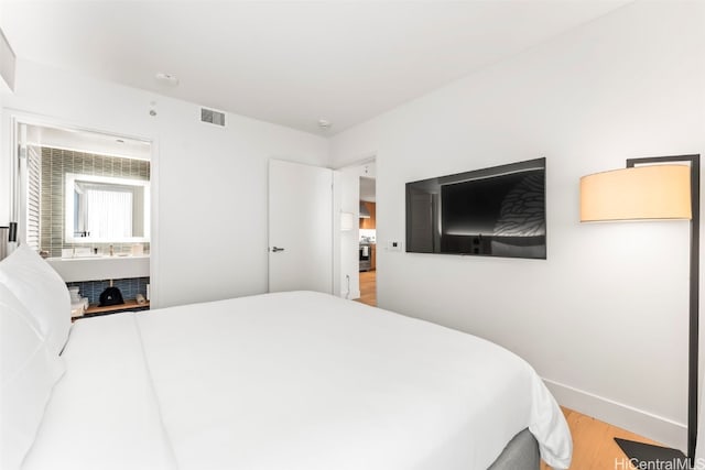 bedroom featuring light wood-style floors, visible vents, and baseboards