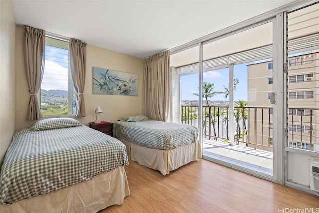 bedroom with a wall of windows, access to outside, and light wood-type flooring