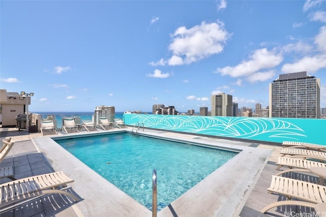 community pool featuring area for grilling, a view of city, and a patio area