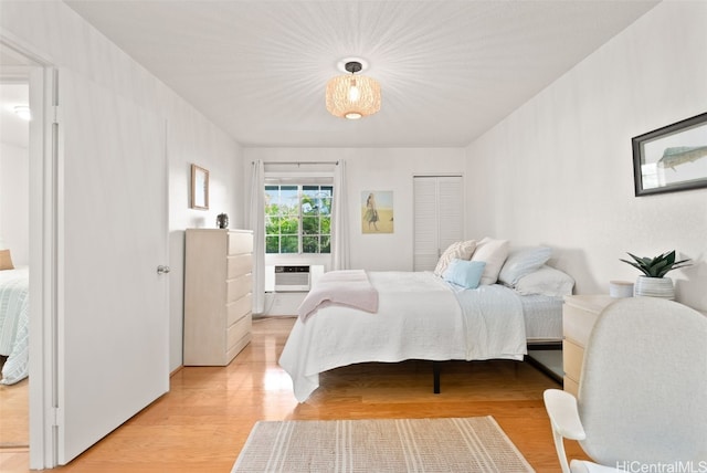 bedroom with light wood finished floors and a wall mounted AC