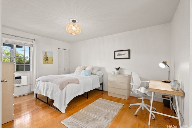 bedroom with a closet, a wall unit AC, and wood finished floors