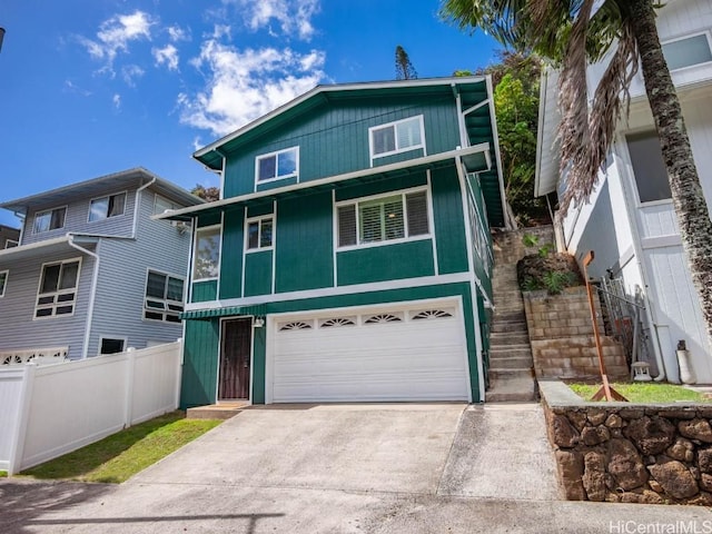 view of front of home with stairway, an attached garage, driveway, and fence