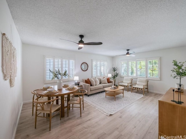 living area featuring a ceiling fan, light wood finished floors, and a healthy amount of sunlight