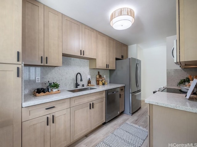 kitchen featuring light wood-type flooring, light brown cabinetry, a sink, backsplash, and stainless steel appliances