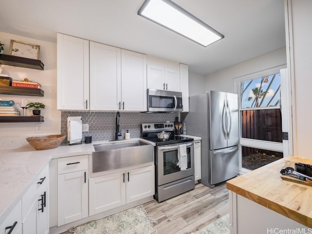 kitchen with a sink, white cabinetry, stainless steel appliances, and open shelves