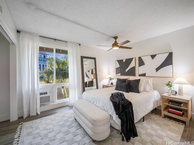 bedroom with cooling unit, a textured ceiling, a ceiling fan, and wood finished floors