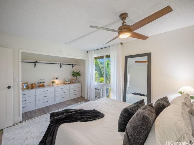 bedroom with light wood finished floors, cooling unit, a textured ceiling, and a ceiling fan