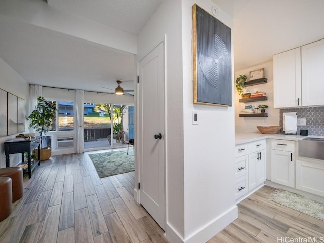 interior space with open floor plan, backsplash, light wood-style floors, and open shelves