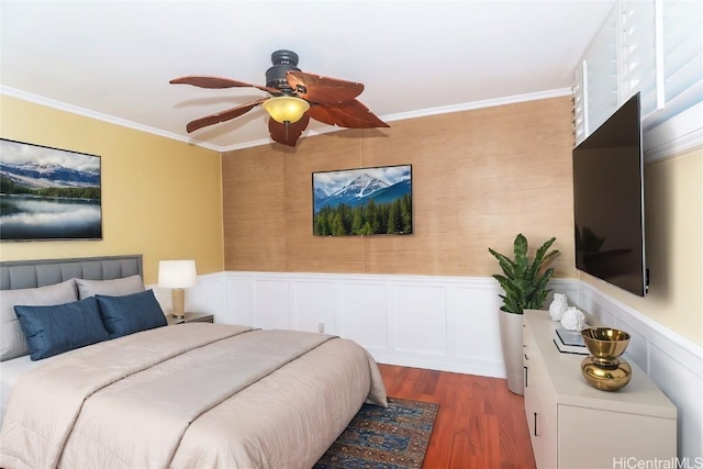 bedroom featuring dark wood finished floors, a wainscoted wall, ceiling fan, and ornamental molding